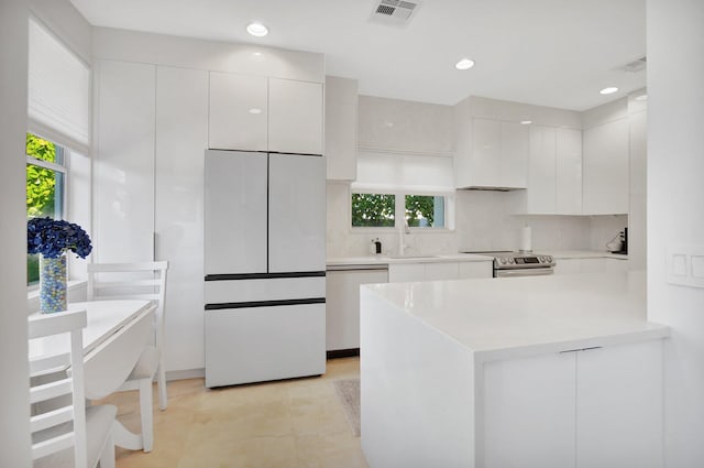 kitchen with tasteful backsplash, kitchen peninsula, white cabinets, and white appliances