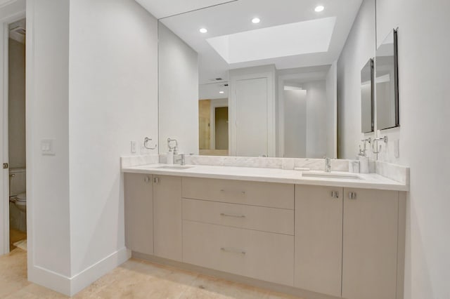 bathroom featuring tile patterned floors, vanity, a skylight, and toilet