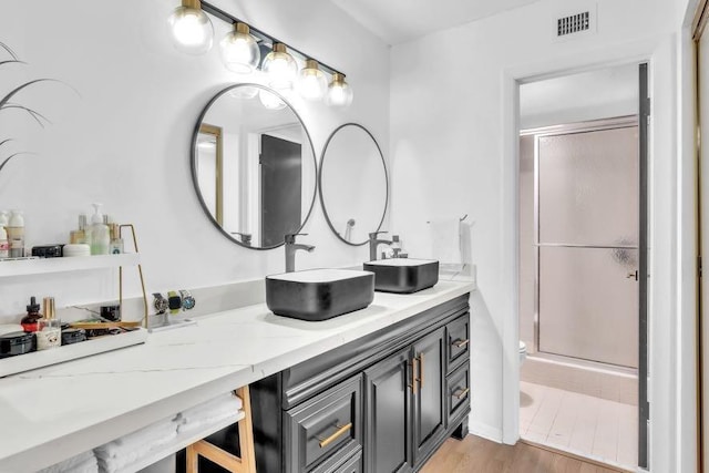 bathroom featuring vanity, toilet, wood-type flooring, and a shower with door