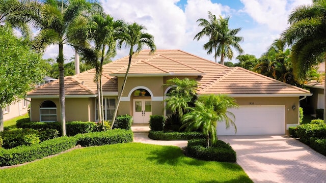 mediterranean / spanish home featuring a front yard, french doors, and a garage