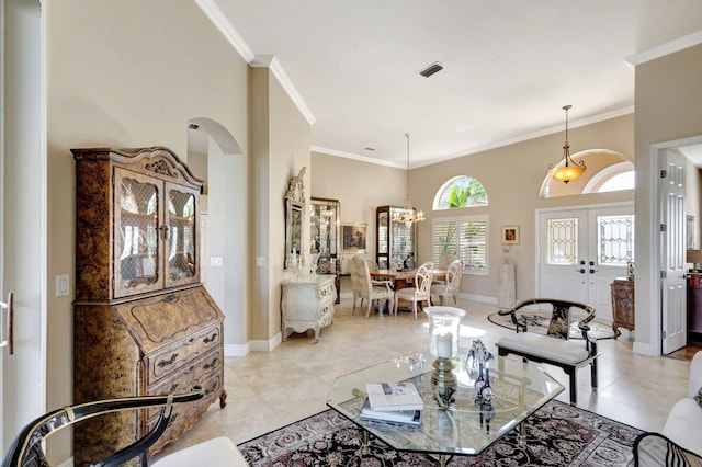 tiled living room featuring ornamental molding, french doors, and a chandelier