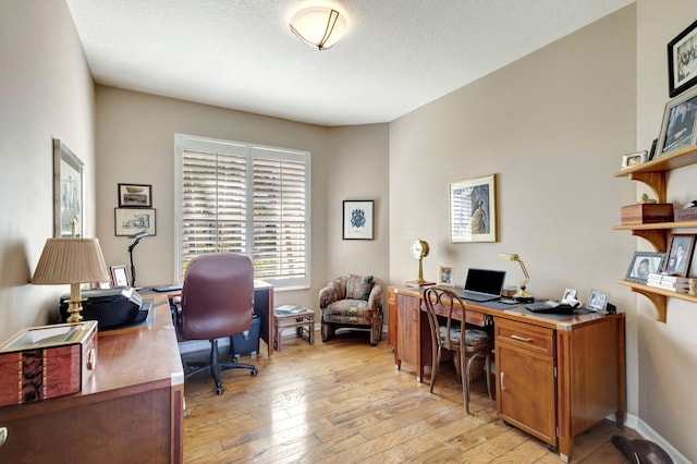 office area with light hardwood / wood-style floors and a textured ceiling