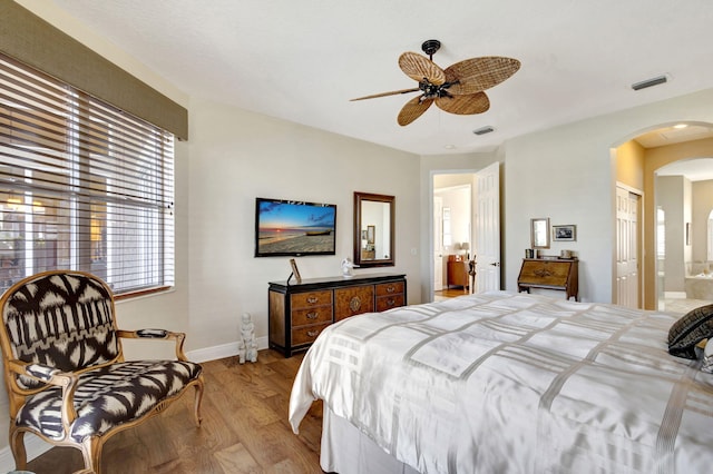 bedroom with ceiling fan, ensuite bath, and light hardwood / wood-style flooring