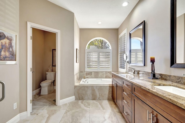 bathroom featuring vanity, tiled bath, and toilet