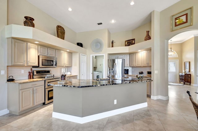 1935 SW Whitemarsh Way, Palm City, FL 34990 - kitchen featuring stainless steel appliances, dark stone counters, high vaulted ceiling, arched walkways, and backsplash