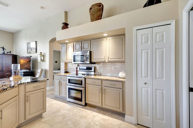 1935 SW Whitemarsh Way, Palm City, FL 34990 - kitchen with appliances with stainless steel finishes, tasteful backsplash, arched walkways, light tile patterned floors, and light stone countertops