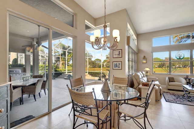 dining area featuring ceiling fan with notable chandelier, light tile patterned floors, and a high ceiling