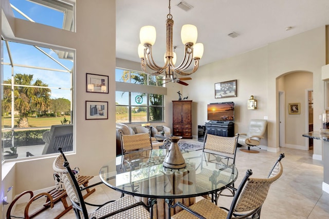 dining room with a towering ceiling, light tile patterned floors, and a notable chandelier