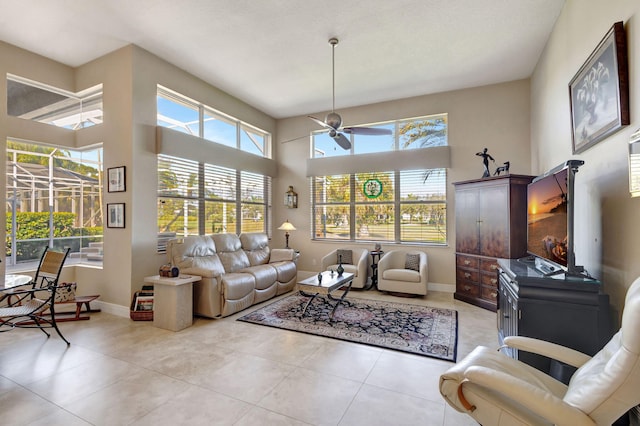 living room with a high ceiling, light tile patterned flooring, a healthy amount of sunlight, and ceiling fan