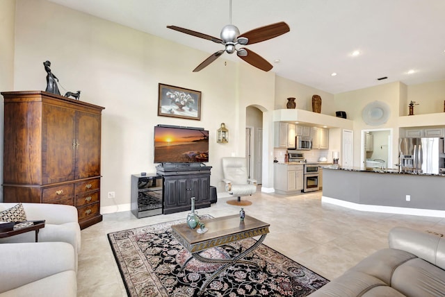 tiled living room with ceiling fan and a high ceiling