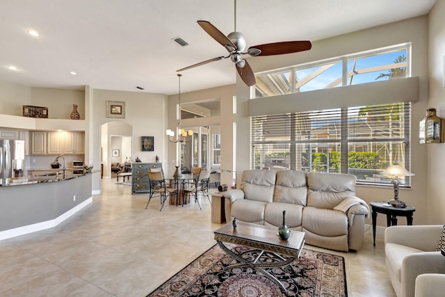 tiled living room with ceiling fan and a high ceiling