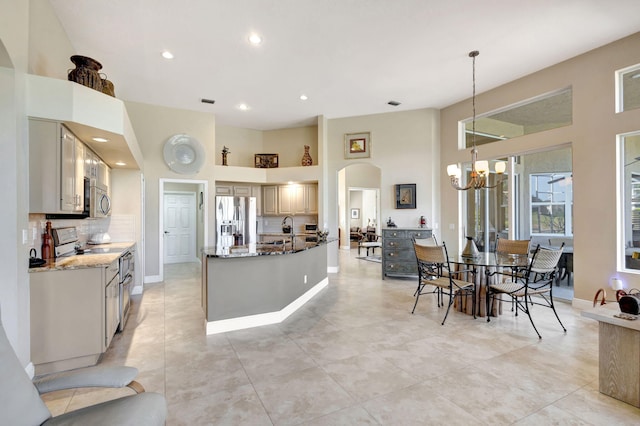 kitchen with hanging light fixtures, stainless steel appliances, decorative backsplash, dark stone counters, and a chandelier