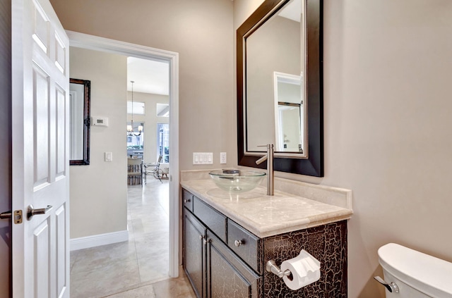 bathroom with an inviting chandelier, vanity, and toilet