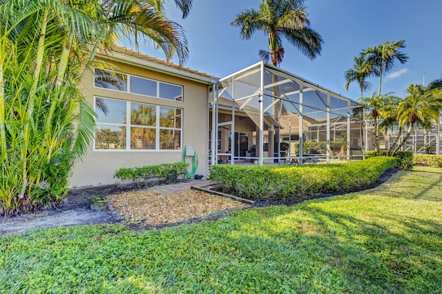 back of house featuring a yard and glass enclosure