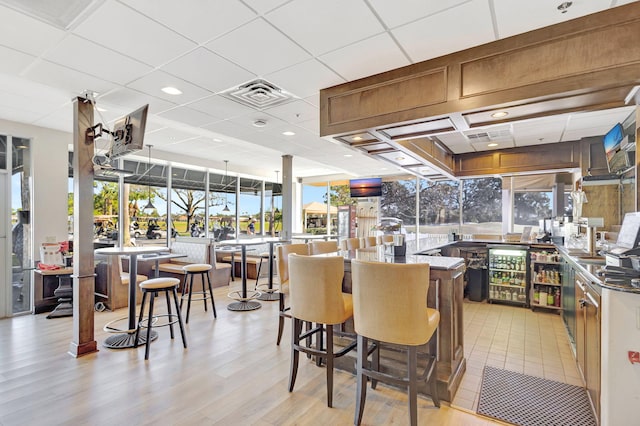 kitchen with light wood-type flooring, a drop ceiling, a kitchen breakfast bar, and kitchen peninsula