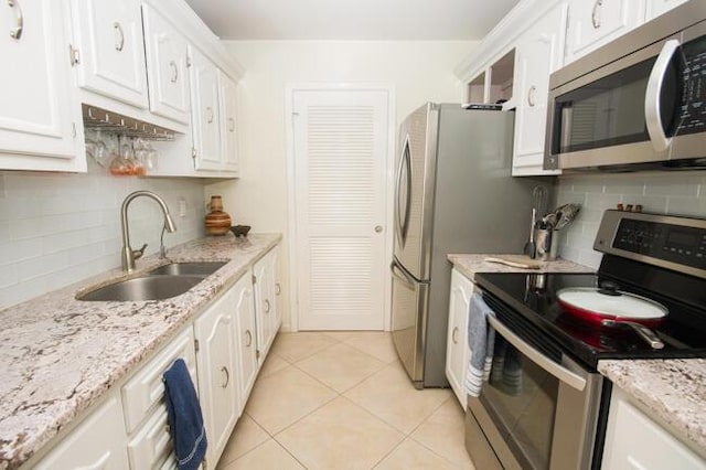 kitchen with white cabinets, light tile patterned floors, stainless steel appliances, and sink