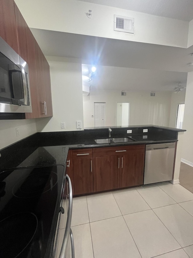 kitchen featuring appliances with stainless steel finishes, ceiling fan, sink, light tile patterned floors, and dark stone countertops