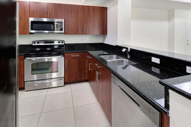 kitchen featuring light tile patterned floors, a sink, appliances with stainless steel finishes, dark stone countertops, and modern cabinets