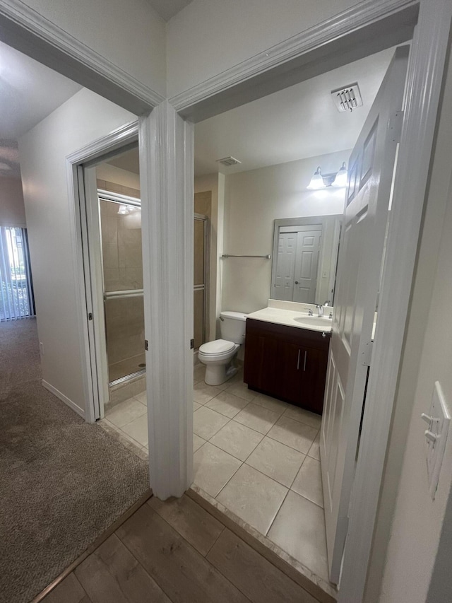 bathroom with tile patterned flooring, vanity, toilet, and walk in shower