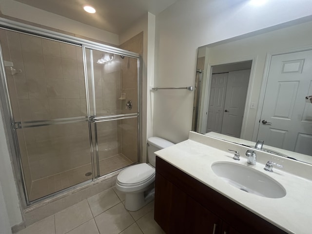 bathroom featuring tile patterned flooring, vanity, an enclosed shower, and toilet