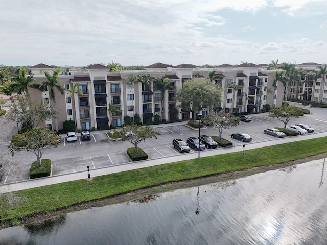 view of building exterior with uncovered parking and a water view