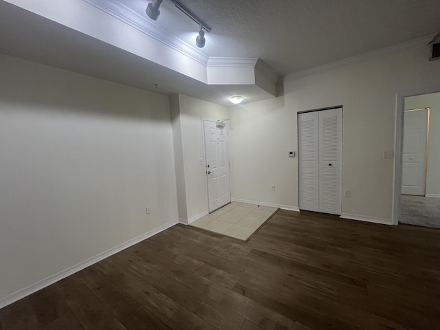 empty room with a textured ceiling, crown molding, hardwood / wood-style floors, and track lighting