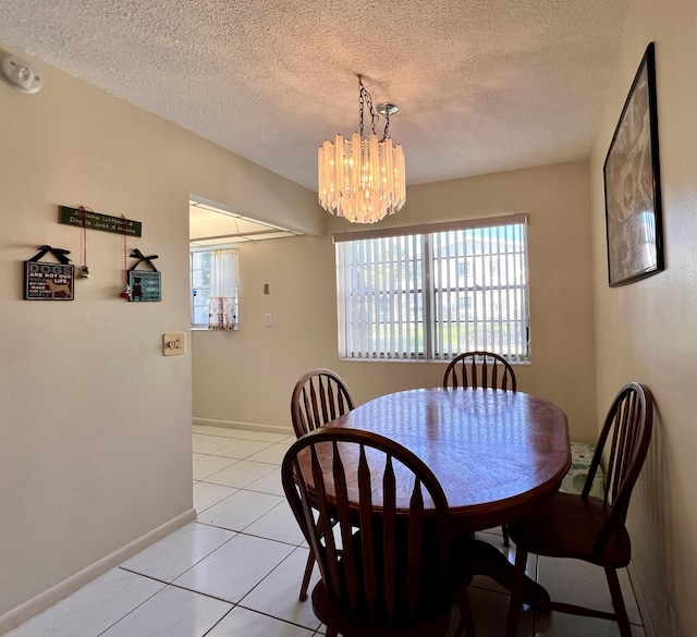 tiled dining space featuring a textured ceiling and a chandelier