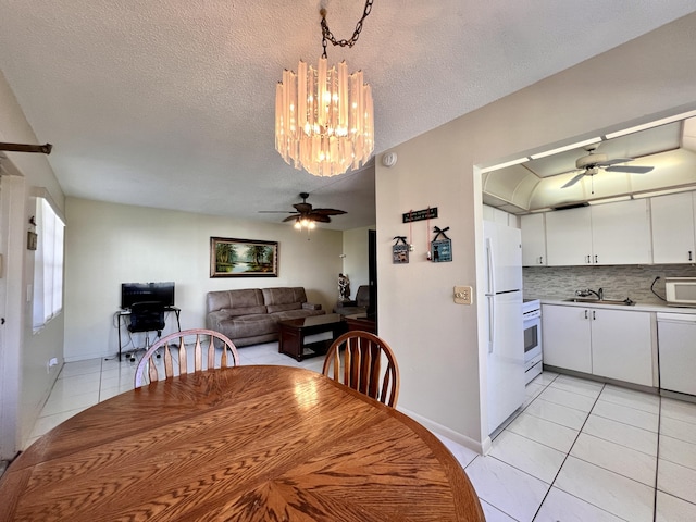 dining area with ceiling fan with notable chandelier, a textured ceiling, light tile patterned flooring, and sink