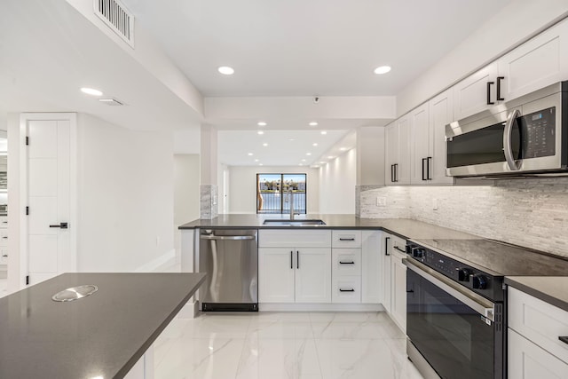 kitchen with kitchen peninsula, appliances with stainless steel finishes, backsplash, sink, and white cabinets