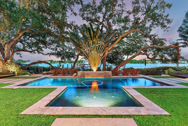 pool at dusk featuring a yard