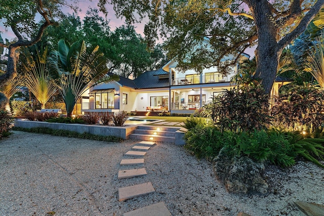 back house at dusk with a balcony