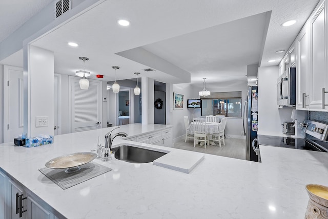 kitchen with white cabinets, sink, hanging light fixtures, and stainless steel appliances