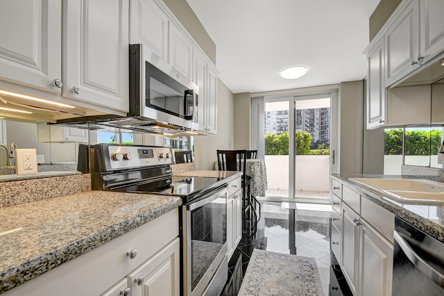 kitchen with white cabinets, sink, light stone countertops, light tile patterned floors, and stainless steel appliances