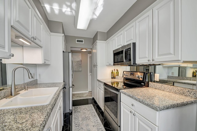 kitchen featuring light stone countertops, stainless steel appliances, sink, dark tile patterned flooring, and white cabinets