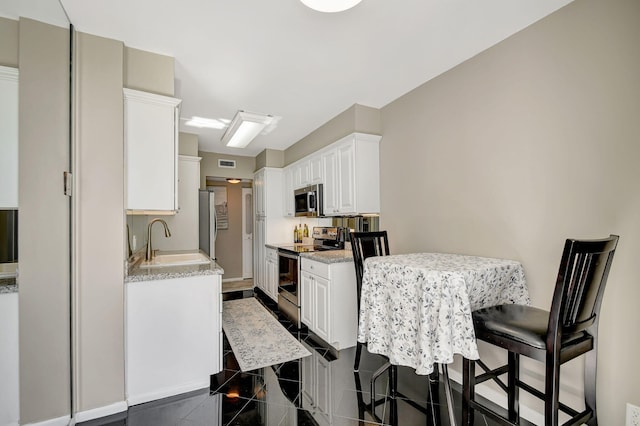 kitchen featuring a breakfast bar area, white cabinetry, sink, and appliances with stainless steel finishes