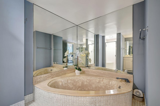 bathroom with tile patterned flooring, vanity, and a relaxing tiled tub