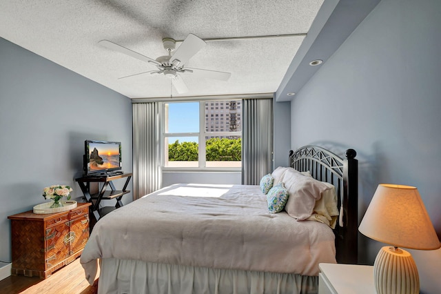 bedroom featuring wood-type flooring, a textured ceiling, and ceiling fan