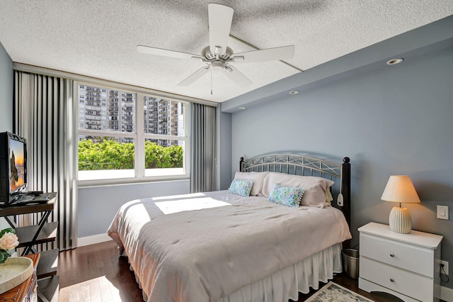 bedroom featuring ceiling fan, hardwood / wood-style floors, and a textured ceiling