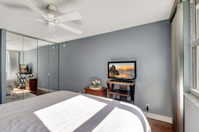 bedroom featuring a textured ceiling, dark hardwood / wood-style flooring, a closet, and ceiling fan