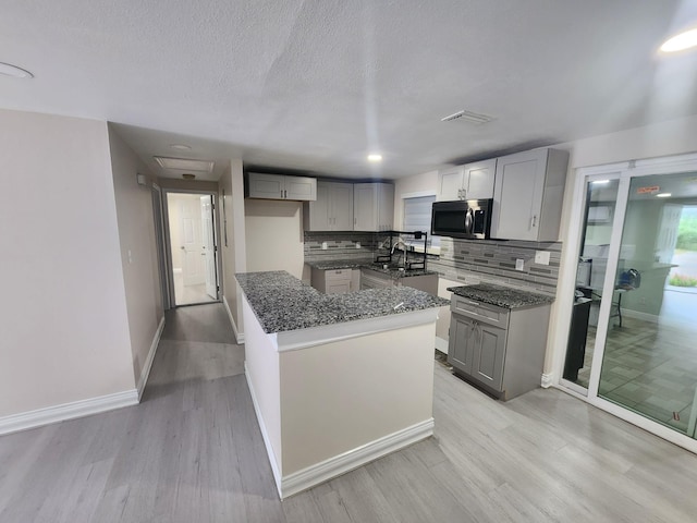 kitchen with backsplash, sink, gray cabinets, light hardwood / wood-style floors, and a kitchen island