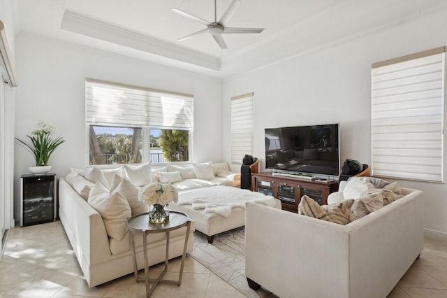 tiled living room featuring a tray ceiling, ceiling fan, and crown molding