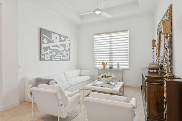 tiled living room with a raised ceiling, ceiling fan, and ornamental molding