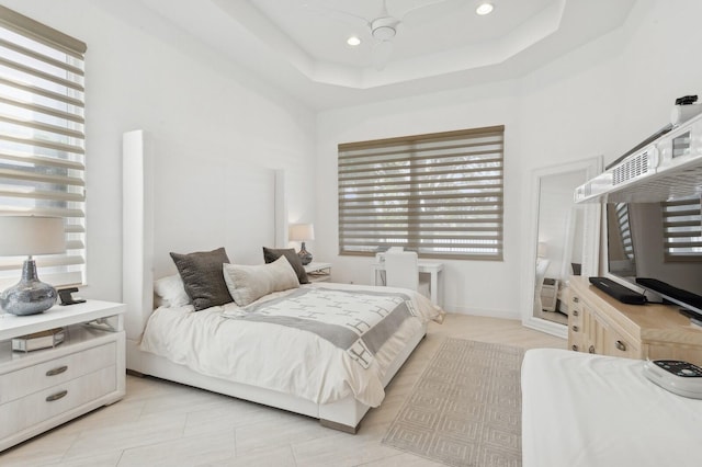 tiled bedroom featuring ceiling fan, a raised ceiling, and a high ceiling