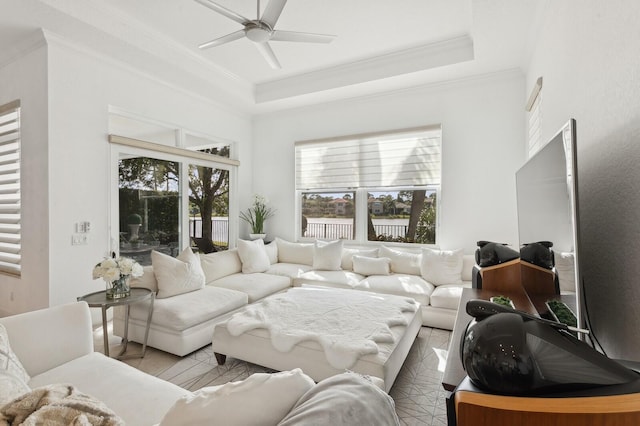 living room featuring ceiling fan, a raised ceiling, and crown molding