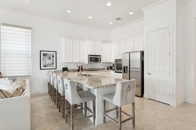 kitchen with ornamental molding, stainless steel appliances, sink, white cabinetry, and a large island