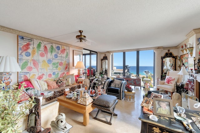 living room with ceiling fan, expansive windows, a water view, and a textured ceiling