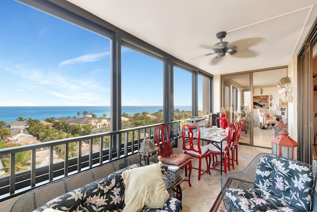 sunroom with ceiling fan and a water view