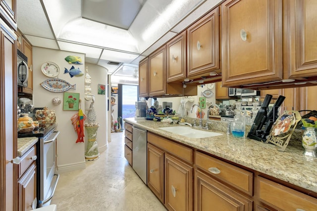 kitchen featuring appliances with stainless steel finishes, a paneled ceiling, light stone counters, and sink