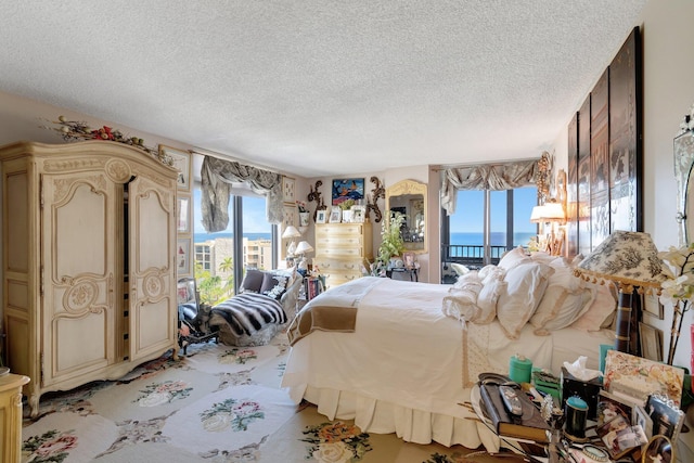 bedroom featuring access to outside, a textured ceiling, and a water view