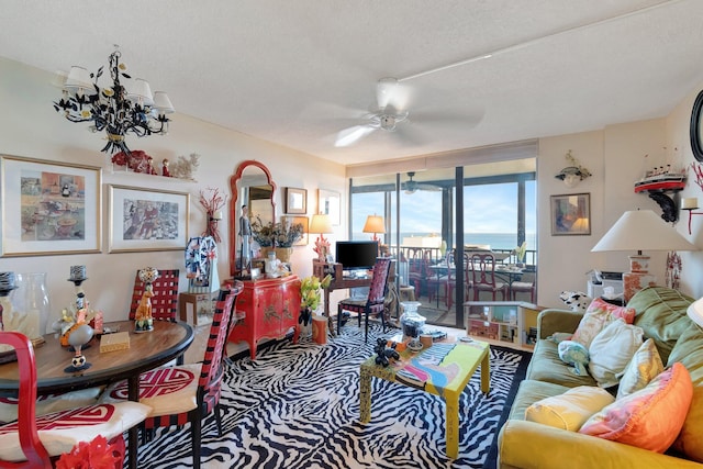 living room with ceiling fan with notable chandelier and a textured ceiling